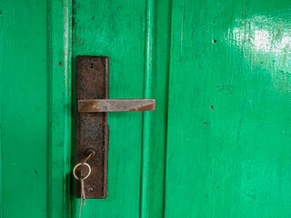 rusty door handle of green door, with key on it