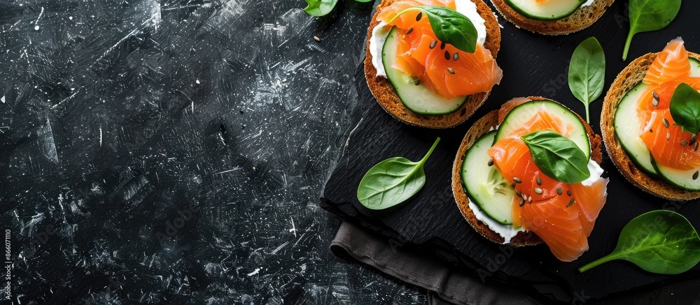 Poster top view of delicious salmon, cream cheese, and cucumber toasts on a black table with ample copy spa