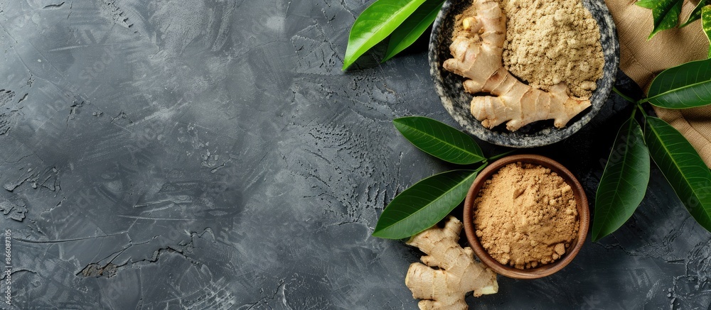 Sticker ginger powder, fresh root, and leaves displayed on a grey table in a flat lay composition, providing