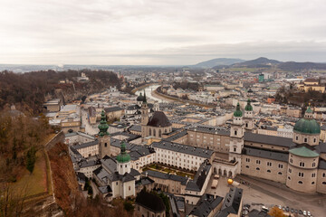 Obraz premium Panoramic view of the old town from the Hohensalzburg fortress. Cloudy and gloomy winter day, St. Peter's Abbey and Baroque Salzburg Cathedral