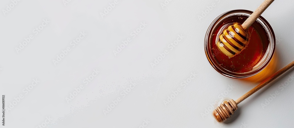 Poster Delicious honey jar with a wooden honey dipper arranged on a white background providing a top view with copy space image.