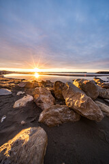 Sonnenaufgang am Meer mit Steinen im Vordergrund