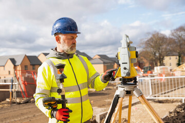 Construction Worker Using Surveying Equipment on Sunny Day