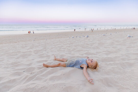 Little boy lying on the sand on Gold Coast beach