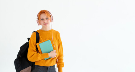 Young college going european redhead hair female nerd student with a backpack, headphones on head,...
