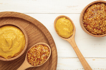 Dijon mustard with french mustard on white wooden background.