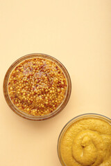 Dijon mustard with french mustard on beige background.