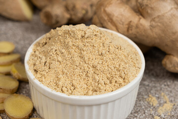 Ground ginger root powder natural spice seasoning on gray stone background