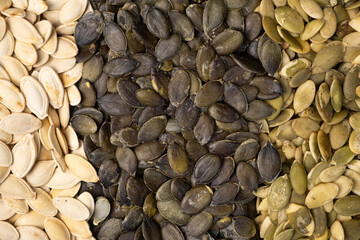 Unpeeled and peeled pumpkin seeds close-up, top view.