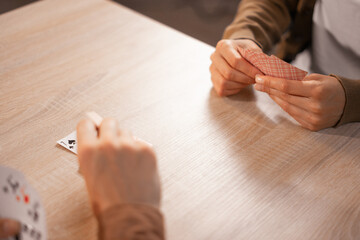 Friends playing cards at table, high angle view, leisure activity, indoor game