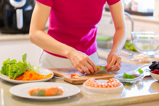 Woman making Vietnamese fresh spring rolls with prawns in kitchen
