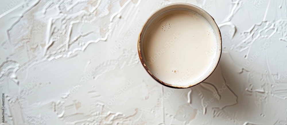 Poster Almond-based alternative milk in an unpeeled glass placed on a white table viewed from above with copy space image.
