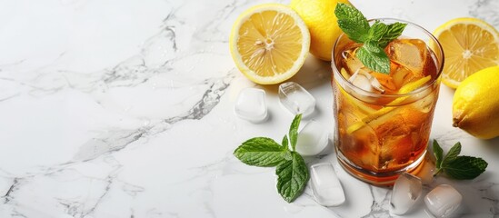 Fototapeta premium Marble table with a glass of iced tea garnished with mint and lemon, representing a refreshing cold drink, surrounded by ample copy space image.