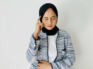 Hardly thinking Asian Muslim woman put her hand to her temple in deep thought isolated by white...