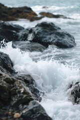 Waves crashing against rocks, with a softly blurred background of a rugged coastline and sea. 