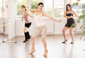 Group of girls dancing energetically in high heels in dance studio