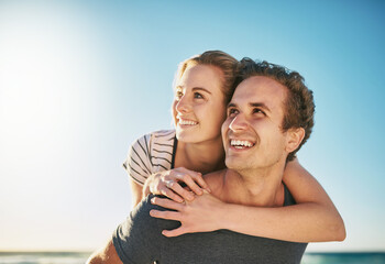 Obraz premium Couple, beach and piggyback for holiday, vacation and thinking of romance, fun and adventure together. Excited young man and woman in USA with ideas for tourism, travel and love outdoor by ocean