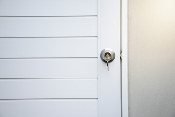 Silver knobs and keys on white modern wooden doors against the gray concrete background for forgot to close the door or lost the key and safety with security concept.