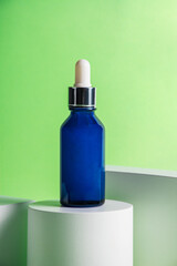 Blue glass cosmetic bottle, Skin care or sunscreen cosmetic with stylish props on green background.