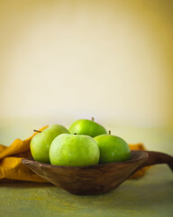 Fresh Green Apples in Rustic Wooden Bowl. A still life composition featuring vibrant green apples nestled in a rustic wooden bowl