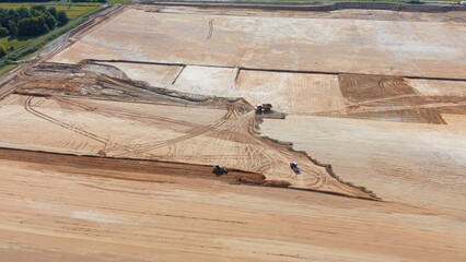 Construction vehicles working on large dirt site