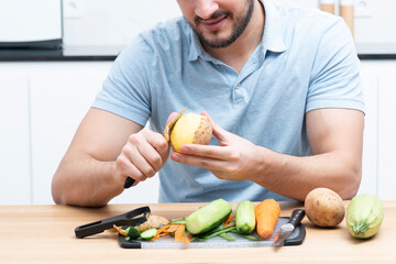 Fototapeta premium Close-up shot of a man peeling vegetables using special vegetable peelers in the kitchen 