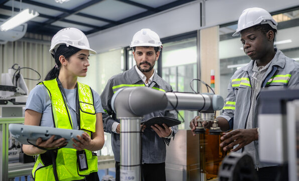 Group of diverse people working on robot programming in robotic and electronic engineering laboratory. Latino engineer team learning and research automated machine with intelligent mechanical control