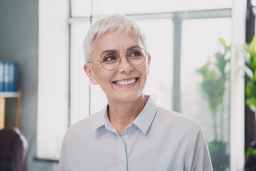 Photo of dreamy good mood age lady recruiter dressed formal shirt smiling working indoors workplace...