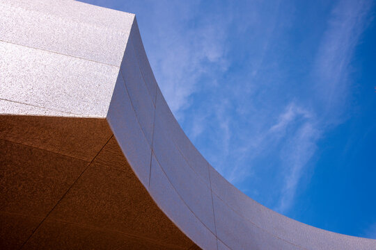 Abstract image of a modern building featuring a curved facade set against a clear blue sky, showcasing the sleek, artful design and architectural innovation of contemporary structures.