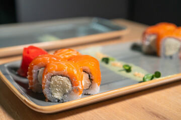 Close-up of delicious Philadelphia sushi on a plate on the kitchen table, with the chef in the background. Concept of food
