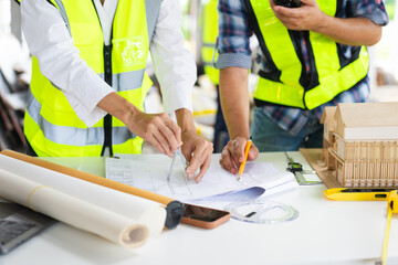 Fototapeta premium Creative architect projecting on the big drawings with architectural project at construction site at desk