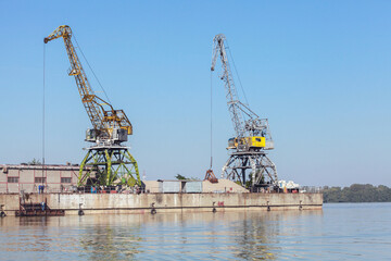 Yellow green portal cranes stand on a quay in harbor