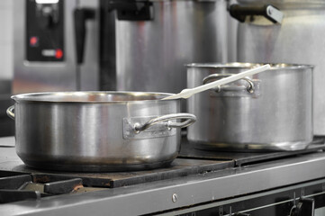 Close up view of casseroles at a commercial kitchen. Preparing and cooking food in a commercial kitchen. Unrecognizable Chefs in the background. High quality photography