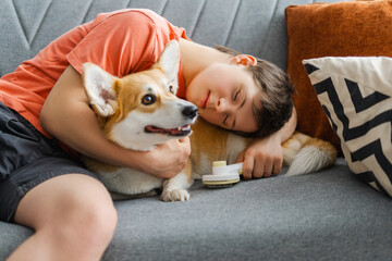 Boy sleeping on sofa while hugging his pet dog after grooming session