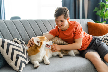 Teenager with down syndrome relaxing on sofa and petting dog