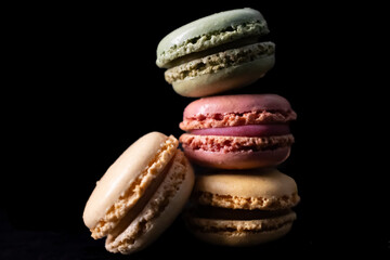 French colored macaroons on each other on dark background. For wallpapers and backgrounds. Macaroons