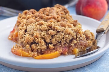 Delicious Peach Crisp or cobbler with brown sugar and oat streusel on plate, horizontal, closeup