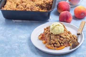 Peach Crisp or cobbler on plate with scoop of vanilla ice cream, horizontal, copy space