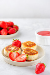 Vegan cheesecakes with strawberries, syrniki, cheese pancakes made from tofu and cashews in a plate. Vertical orientation.