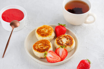 Cheesecakes with berries, sweet sauce, cashew, tofu and cup of tea. Healthy breakfast. Syrniki, cheese pancakes. Vegan, sugar, lactose and gluten free.