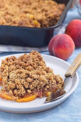 Delicious Peach Crisp or cobbler with brown sugar and oat streusel on plate, vertical