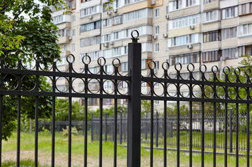 Metal fence in the city park. Decorative black iron guardrail for protection, close up