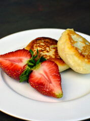 Syrniki: Balkan Cottage Cheese Pancakes with strawberries and honey. The concept of tasty healthy summer breakfast.