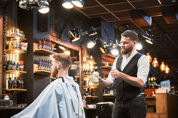 Professional barber spraying aftershave lotion on client's nape. Back view of fresh haircut from experienced hairdresser. Male hairstylist using special equipment for styling.