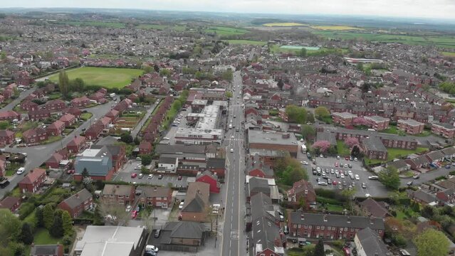 Aerial footage of the Leeds based town of Garforth in West Yorkshire in the UK, showing the main street road on a bad weather dank day