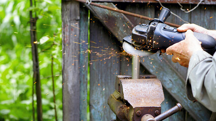 The worker cuts metal, steel with a grinder. the pipe is clamped in a vice, sparks fly. close-up, the hands of a man using a grinder to cut a pipe, bright flashes flying in different directions.