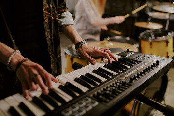 Closeup of hands of unrecognizable male musician playing synthesizer in rock band