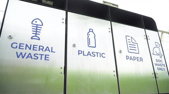 Separate waste containers for general waste, plastic, paper and dog waste in urban environment.