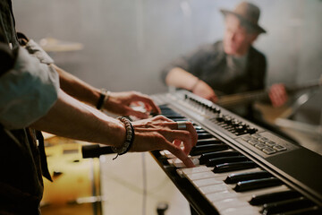 Closeup of hands of unrecognizable rock musician playing synthesizer on stage, copy space