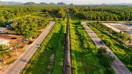 Naklejka premium aerial view Railway tracks in the suburbs. The railway line crosses the river. Train transportation. Railway tracks and road from above that is a long way Through natural areas in rural areas